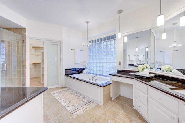 full bathroom featuring an inviting chandelier, vanity, a spacious closet, a bath, and a stall shower