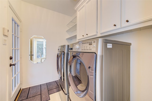 laundry room featuring separate washer and dryer, baseboards, and cabinet space