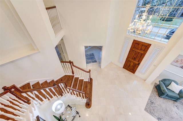 foyer entrance featuring an inviting chandelier, tile patterned floors, a high ceiling, and stairs