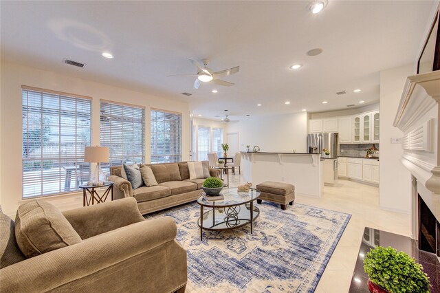 living room with a ceiling fan, visible vents, plenty of natural light, and light tile patterned flooring