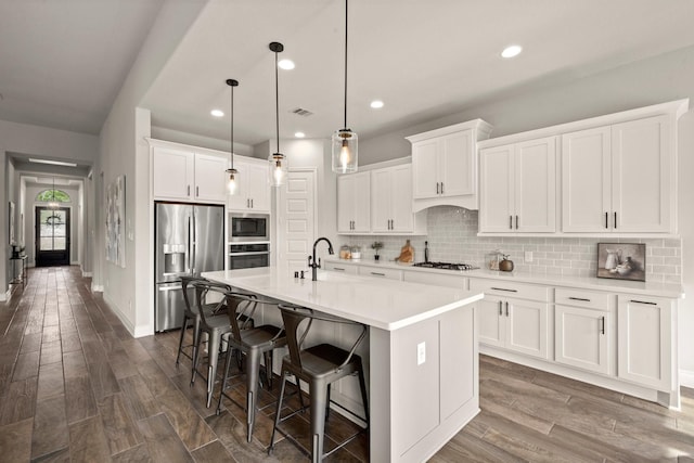 16711 Arboleda Dr, Humble, TX 77346 - kitchen featuring stainless steel appliances, decorative backsplash, a kitchen bar, white cabinetry, and light countertops
