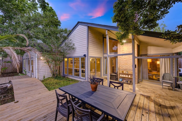 deck at dusk featuring an outdoor structure and outdoor dining area