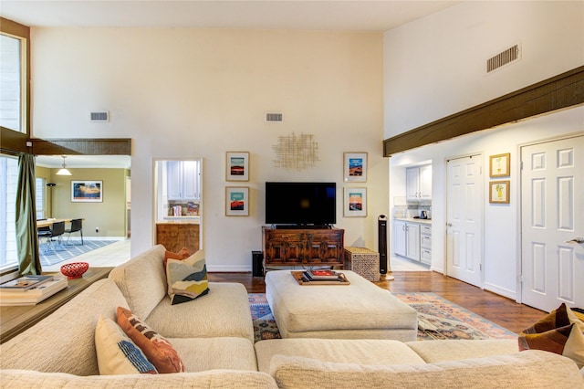living area featuring high vaulted ceiling, wood finished floors, and visible vents