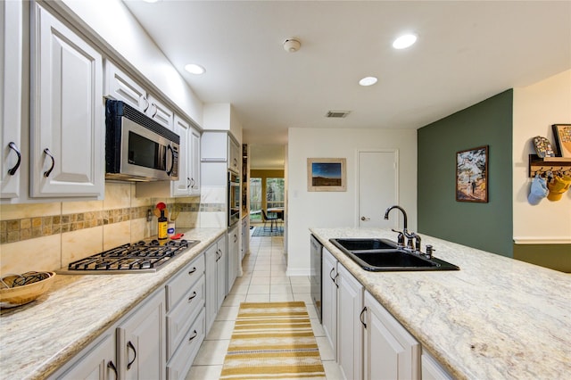 kitchen with backsplash, visible vents, appliances with stainless steel finishes, a sink, and light tile patterned floors