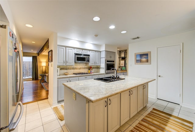 kitchen featuring visible vents, appliances with stainless steel finishes, tasteful backsplash, a sink, and light tile patterned flooring