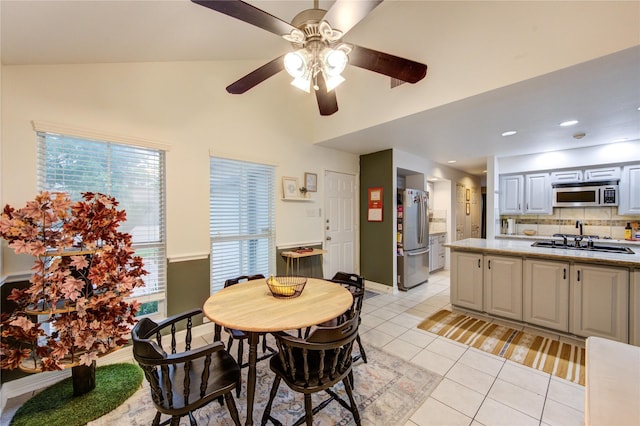 dining space with a ceiling fan, baseboards, vaulted ceiling, and light tile patterned floors