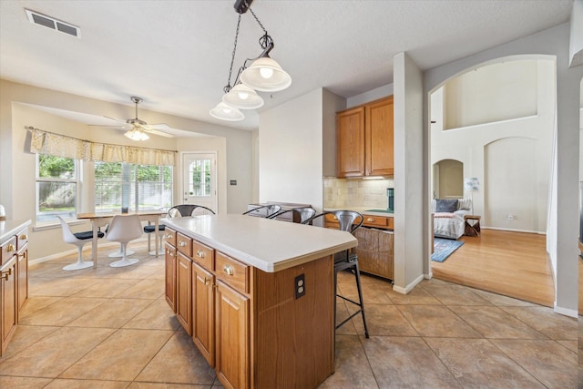 13907 Carrington Ln, Cypress, TX 77429 - kitchen featuring a kitchen breakfast bar, a center island, arched walkways, light countertops, and backsplash