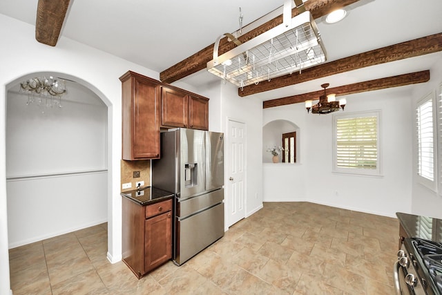 kitchen with arched walkways, a chandelier, beamed ceiling, appliances with stainless steel finishes, and baseboards