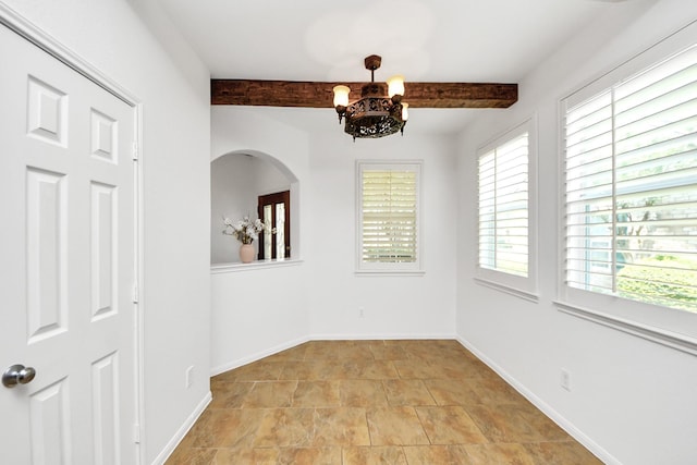 unfurnished dining area with a chandelier, arched walkways, beamed ceiling, and baseboards