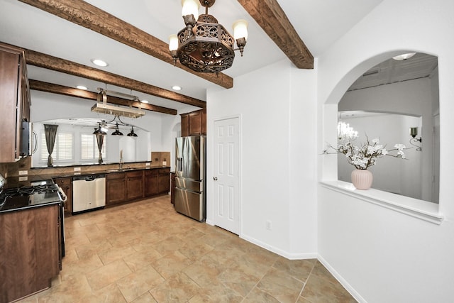kitchen with beamed ceiling, an inviting chandelier, a sink, dark countertops, and appliances with stainless steel finishes