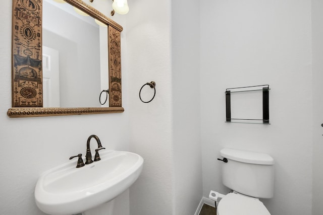 bathroom with toilet, a sink, and baseboards