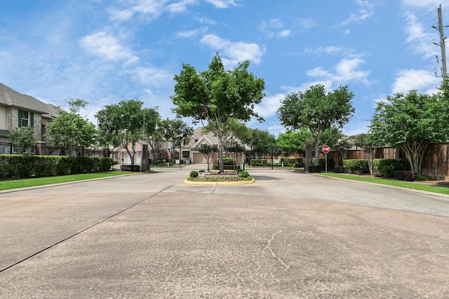 view of street featuring curbs, a gated entry, traffic signs, and a residential view