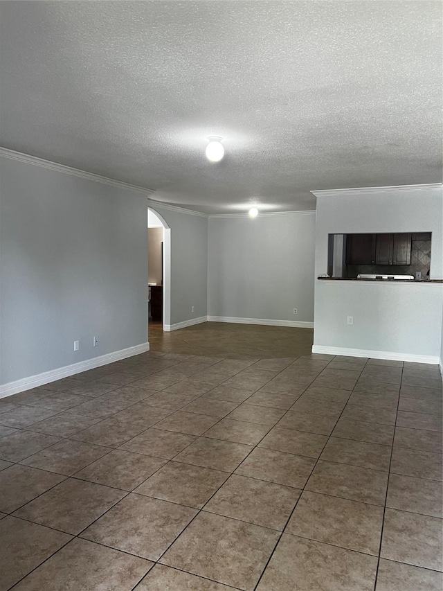 tiled spare room with ornamental molding, arched walkways, a textured ceiling, and baseboards