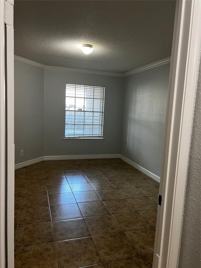 unfurnished room with ornamental molding, a textured ceiling, dark tile patterned floors, and baseboards