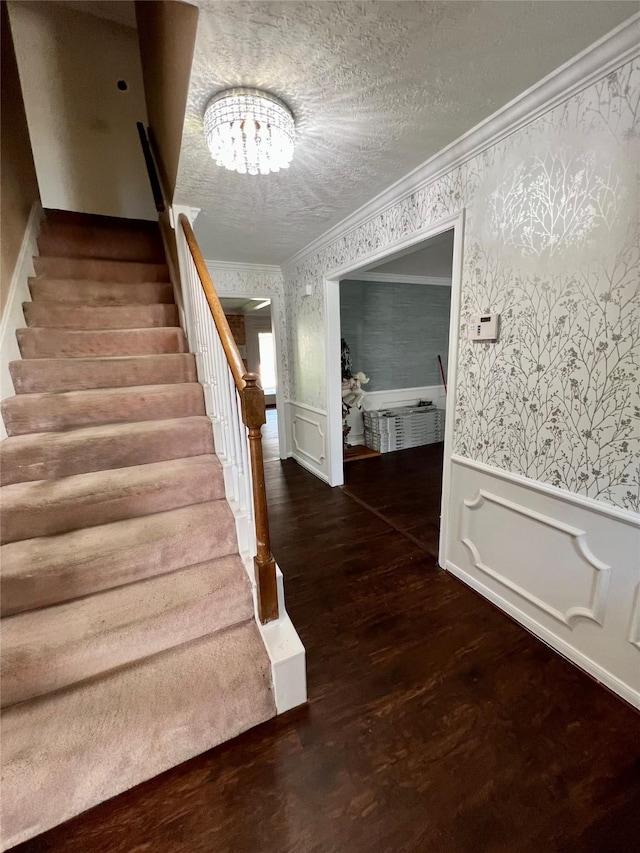 16418 York Minster Dr, Spring, TX 77379 - stairs featuring wallpapered walls, crown molding, a wainscoted wall, a chandelier, and wood finished floors