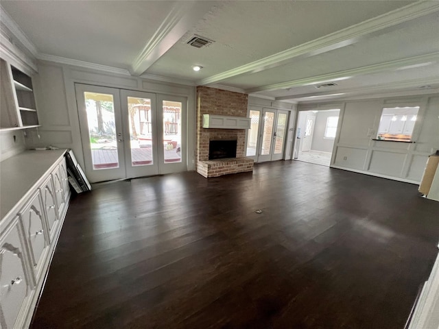 16418 York Minster Dr, Spring, TX 77379 - unfurnished living room featuring french doors, crown molding, beamed ceiling, a decorative wall, and dark wood-style floors