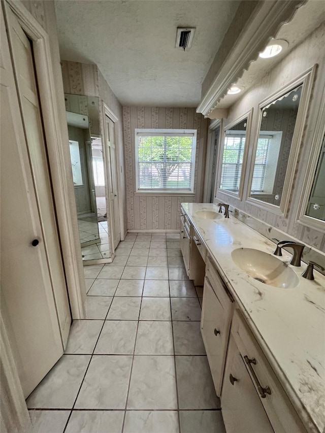 16418 York Minster Dr, Spring, TX 77379 - bathroom with double vanity, tile patterned flooring, baseboards, wallpapered walls, and a textured ceiling