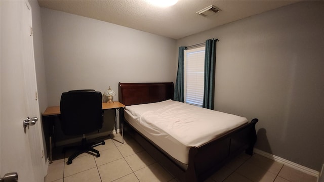 bedroom with light tile patterned floors, visible vents, baseboards, and a textured ceiling