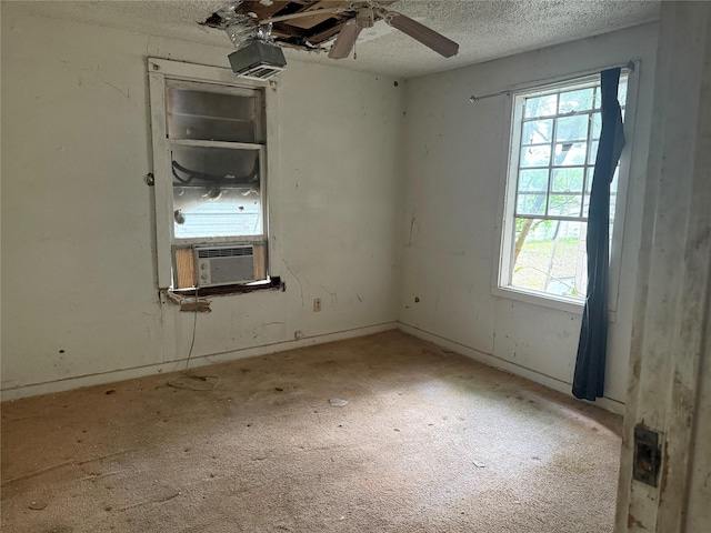 carpeted spare room with a textured ceiling, ceiling fan, a wealth of natural light, and cooling unit