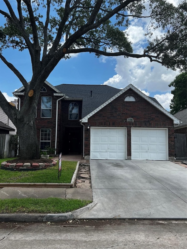 traditional home with driveway, brick siding, a shingled roof, and an attached garage