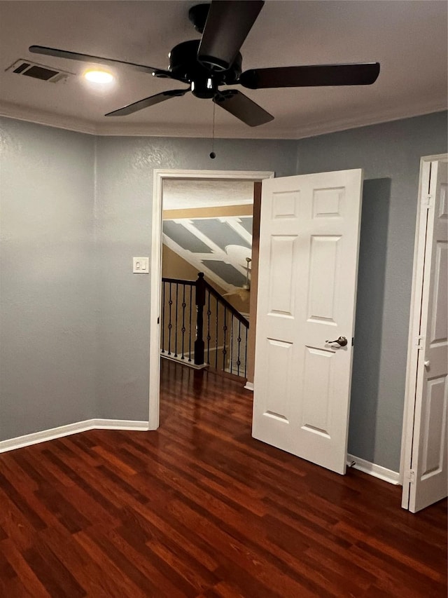 spare room with crown molding, a ceiling fan, visible vents, baseboards, and wood finished floors