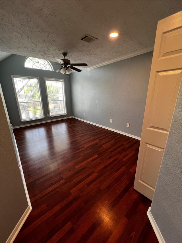 empty room with a textured ceiling, visible vents, baseboards, dark wood-type flooring, and a ceiling fan