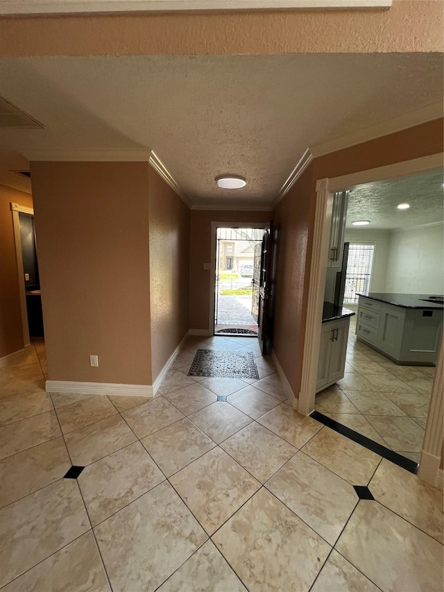 entryway with a wealth of natural light, ornamental molding, a textured ceiling, and baseboards