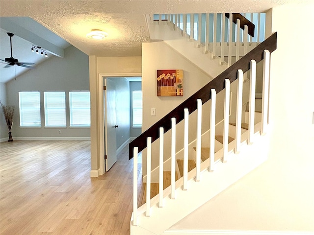 stairs featuring baseboards, wood finished floors, ceiling fan, and lofted ceiling