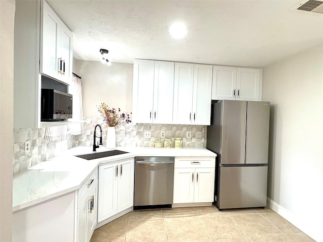 kitchen with white cabinets, appliances with stainless steel finishes, decorative backsplash, and a sink