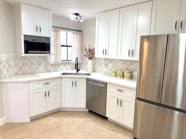 kitchen featuring white cabinetry, backsplash, appliances with stainless steel finishes, and a sink