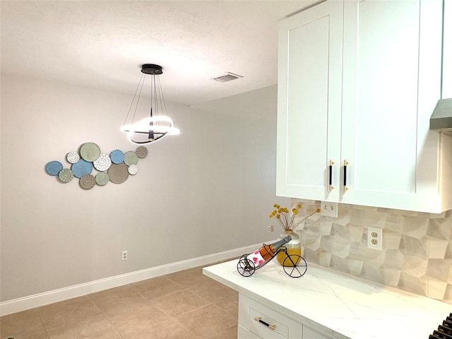 kitchen with light tile patterned floors, light stone countertops, white cabinets, and decorative backsplash