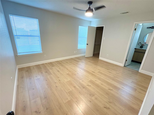 unfurnished bedroom with ensuite bath, visible vents, light wood finished floors, and baseboards