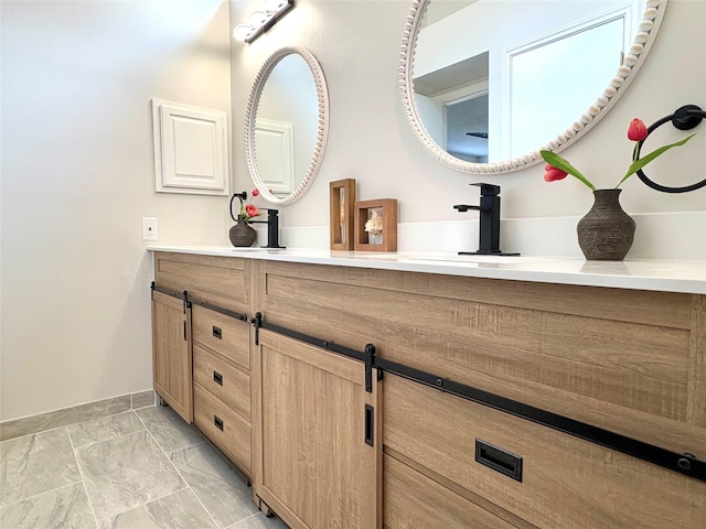 bathroom with double vanity, marble finish floor, and baseboards
