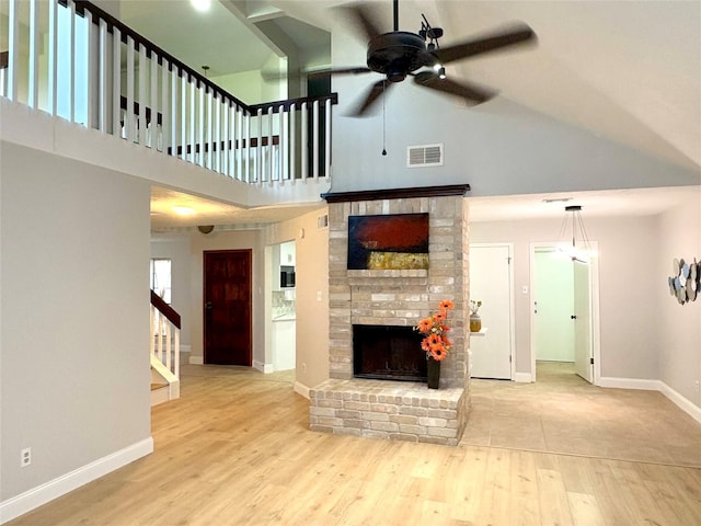 unfurnished living room featuring a ceiling fan, high vaulted ceiling, visible vents, and a fireplace
