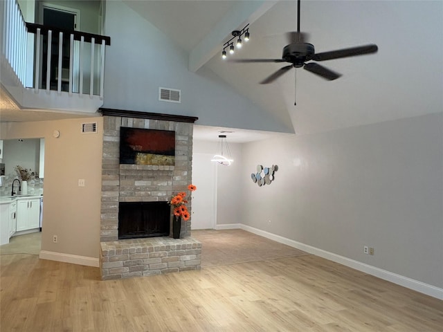 unfurnished living room with a sink, visible vents, light wood-style flooring, and high vaulted ceiling
