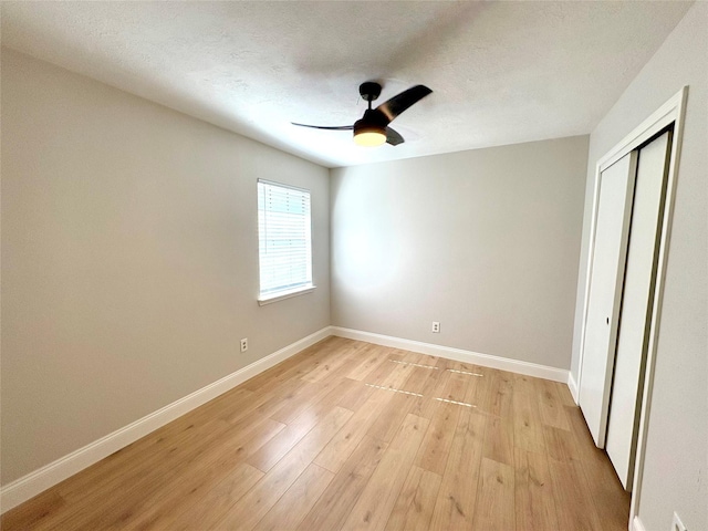 unfurnished bedroom with a closet, ceiling fan, baseboards, and light wood-type flooring