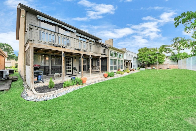 back of property featuring a patio, fence, a chimney, and a lawn