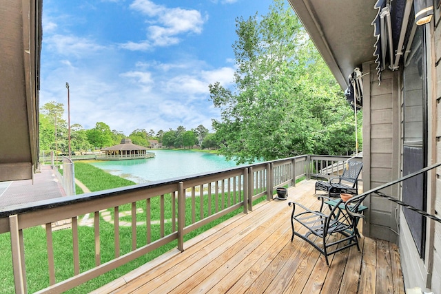 wooden terrace featuring a water view and a yard