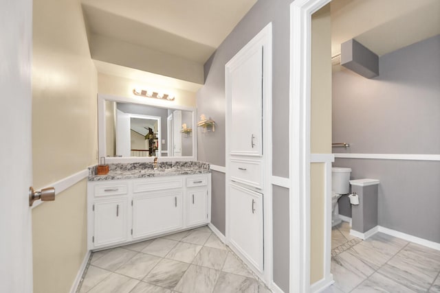 bathroom with baseboards, toilet, vanity, and marble finish floor