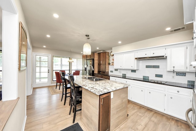 kitchen featuring recessed lighting, light wood finished floors, a sink, black electric cooktop, and visible vents