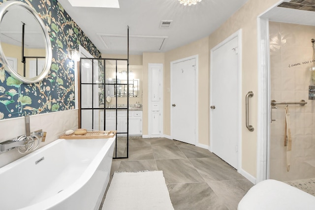 bathroom with visible vents, a shower stall, a freestanding bath, and wallpapered walls