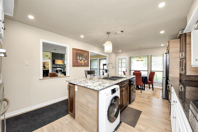200 Old Bridge Lk, Houston, TX 77069 - kitchen featuring visible vents, light wood-style floors, washer / clothes dryer, a center island with sink, and a sink