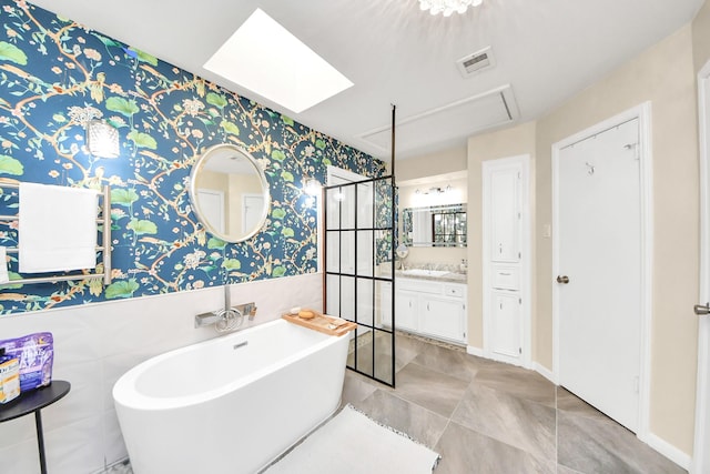 bathroom featuring visible vents, a stall shower, wallpapered walls, a freestanding bath, and a skylight