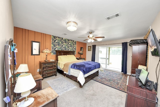 bedroom with an accent wall, visible vents, ceiling fan, access to exterior, and carpet floors
