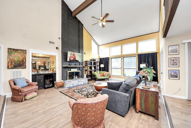 living area with beamed ceiling, visible vents, wood finished floors, a ceiling fan, and high vaulted ceiling