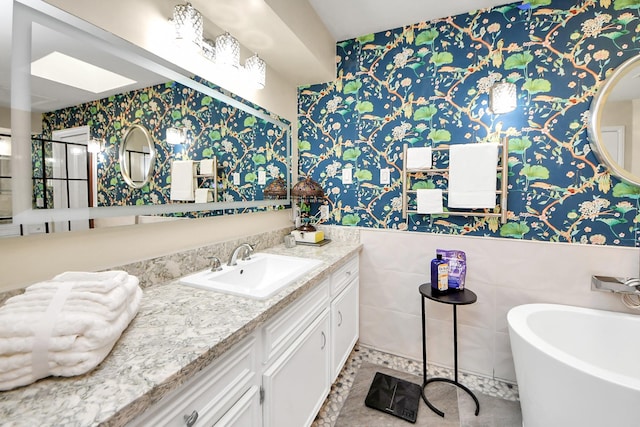 full bath featuring a soaking tub, wallpapered walls, and vanity
