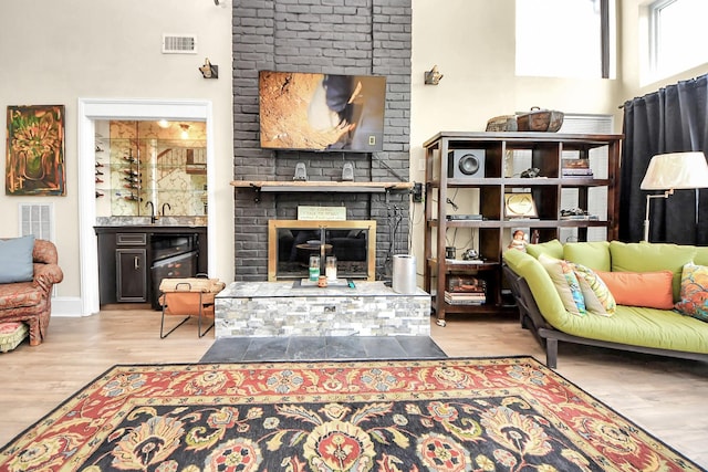 sitting room featuring a brick fireplace, visible vents, and wood finished floors