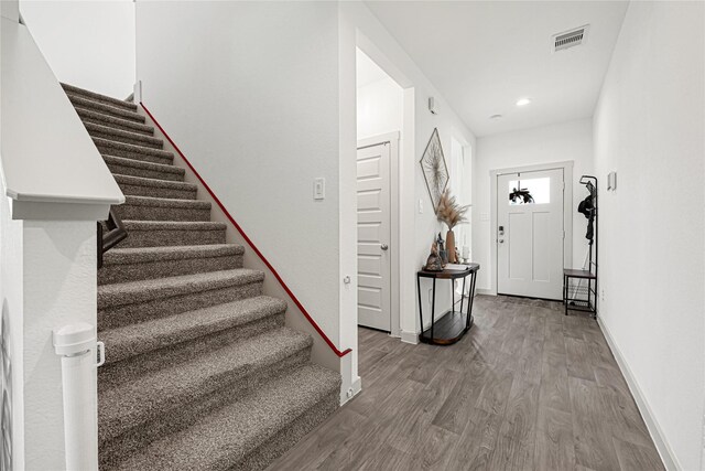 foyer featuring baseboards, stairs, wood finished floors, and visible vents