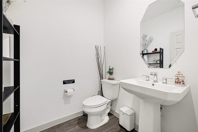 bathroom featuring baseboards, a sink, wood finished floors, and toilet