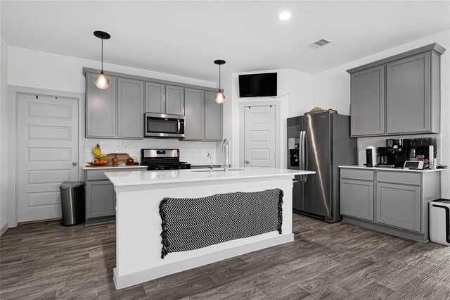 kitchen with gray cabinetry, stainless steel appliances, dark wood finished floors, and a sink